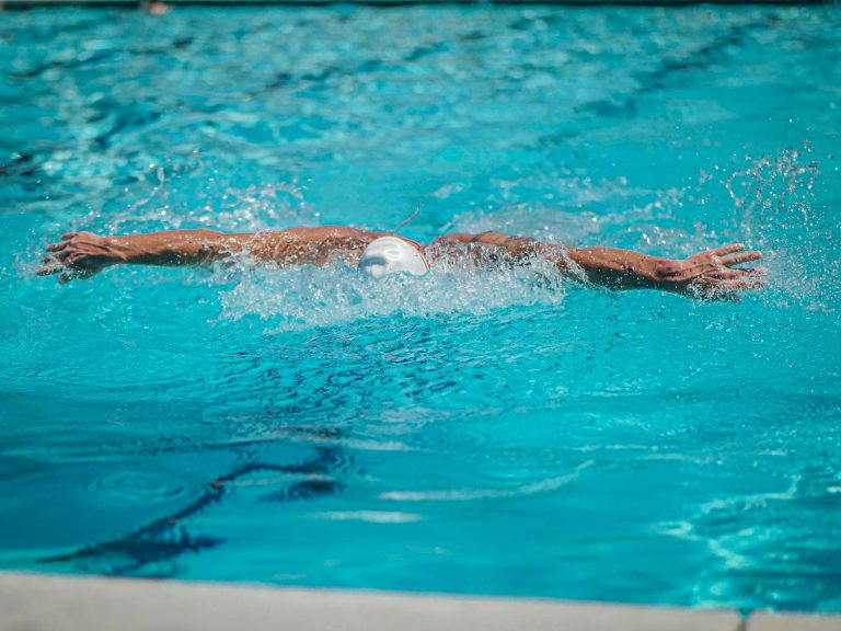 An athlete demonstrates the butterfly stroke in a swimming pool, showcasing skill and effort.