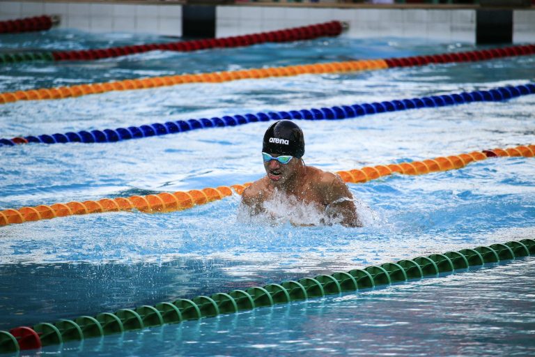 Male athlete swimming in a pool during a race, showcasing water sports action.