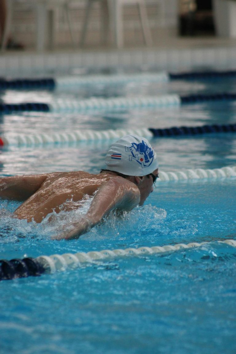Male swimmer performing butterfly stroke in a competitive swimming pool.